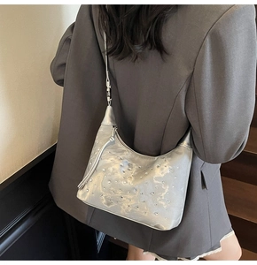 Close-up of sparkling silver rhinestone hobo bag with sleek shoulder strap on a model