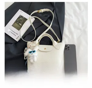 Detailed shot of white lychee leather tote bag featuring a cute plush bunny charm accessory