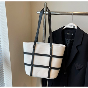 Detail of canvas tote bag with black leather straps and silver metal stud embellishments