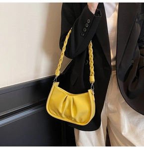 Close-up of yellow pleated underarm bag with a unique thick woven shoulder strap