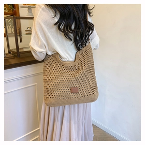 Detail shot of a khaki woven tote bag with hollow patterns and a brown leather patch