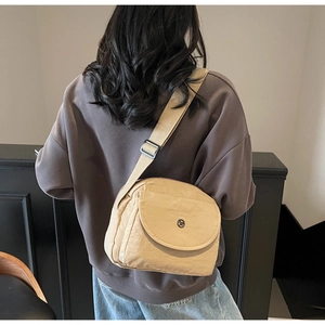 Detailansicht der beigen Nylon-Umhängetasche mit verstellbarem Riemen und Metalllogo