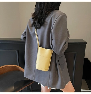 Close-up of yellow pebbled leather crossbody phone bag shown on a model's shoulder