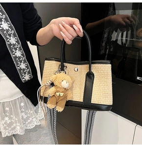 Détail d'un sac en paille avec garniture en cuir noir et charmant ours en peluche