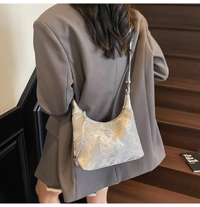 Detail of silver pleated crescent bag with metallic finish and beaded texture on model