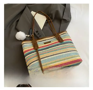 Detail of colorful striped straw bag with leather straps and decorative tassel charms