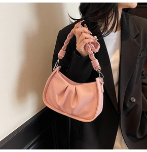 Close-up of pink pleated cloud bag with textured finish and woven handle detail