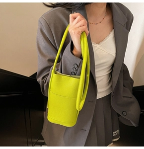 Detail of lime green bucket bag featuring premium lychee grain leather and long handle