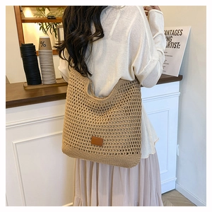Close-up of the handcrafted woven texture and leather logo detail on a khaki tote bag