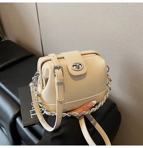 Close-up of off-white lychee leather texture and silver metal twist lock on a bucket bag