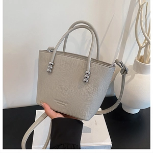 Detail of grey bucket bag with lychee texture and silver bead hardware handles