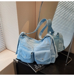 Détail du cabas en velours côtelé bleu clair avec plusieurs poches zippées et œillets