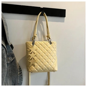 Détail du sac cabas matelassé jaune clair avec breloques étoiles et texture cuir