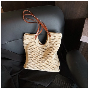 Detailed view of woven beige tote bag with premium brown leather handles and silver rivets