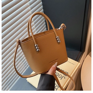 Detail of tan lychee grain leather bucket bag with silver ball charms and shoulder strap