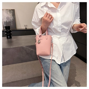 Détail d'un mini sac seau en cuir rose avec pendentif coeur argenté et gaufrage mode