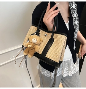 Détail du sac seau en paille tissée avec garniture en cuir, breloque ours et sangle