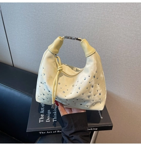 Detail of cream pleated handbag featuring rhinestones and a silver metal buckle closure