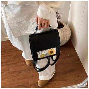 Detail of black leather bag featuring a transparent sunflower window display with top handle