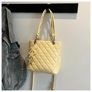 Détail du sac seau matelassé jaune pâle avec breloques étoiles dorées et bandoulière