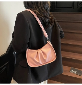 Detail of pink pleated cloud bag with litchi texture and woven leather shoulder strap