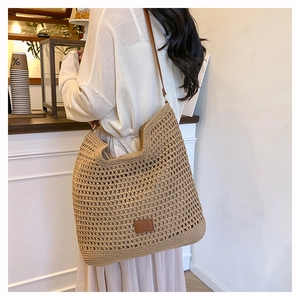 Close-up of woven tote bag with brown leather straps and detail in a cafe setting
