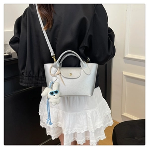 Close-up of silver lychee leather tote bag with fluffy bunny pendant and shoulder strap