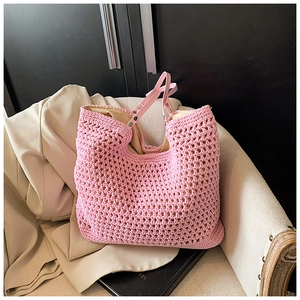 Detail of pink hand-woven crochet tote bag with leather straps on a beige chair