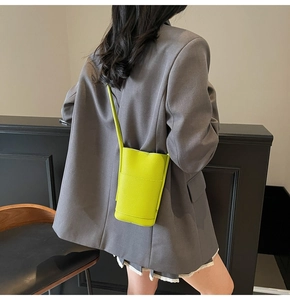 Detail view of neon yellow crossbody phone bag with lychee texture on grey blazer jacket