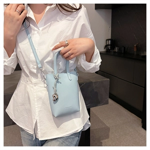 Détails du sac bleu ciel en cuir grainé avec pendentif coeur argenté et bandoulière amovible