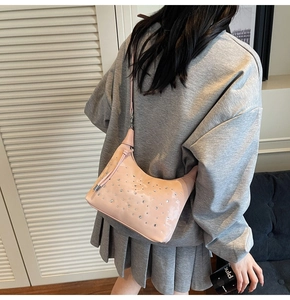 Detailed view of pink rhinestone dumpling bag worn over the shoulder in soft light
