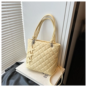 Détail de sac seau matelassé beige avec breloques étoiles et doubles poignées