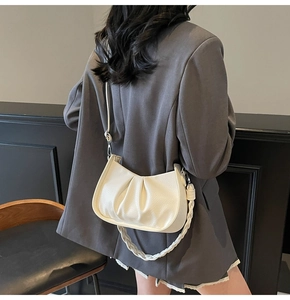 Close-up of white lychee leather pleated cloud bag with silver hardware on a model