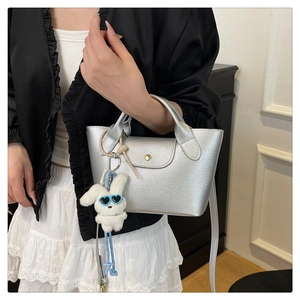 Silver textured tote bag detail featuring white plush bunny charm and luxury flap closure