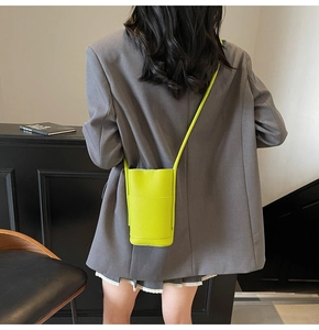 Fluorescent green crossbody phone bag with lychee texture shown on model for size scaling