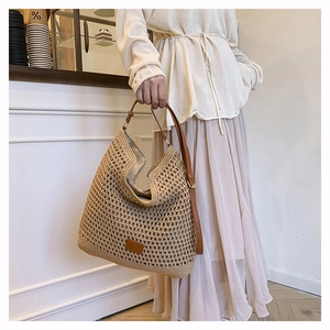 Detail of woven khaki hobo bag with brown leather strap and branding patch