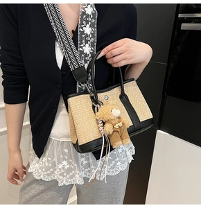 Détail du sac en paille tissée avec bordure en cuir noir et bandoulière géométrique