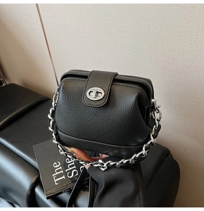 Detail of black lychee grain leather handbag with silver clasp and metal chain strap