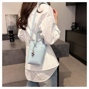 Détail du mini sac bleu clair en cuir grainé avec breloque cœur et bandoulière réglable