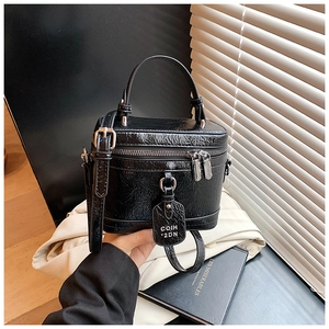 Close-up of black glossy patent leather texture and branding tag on small square bag