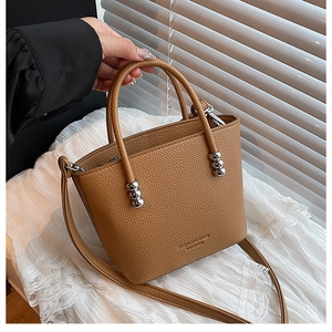 Detail view of brown pebble leather bucket bag with silver bead hardware and top handles