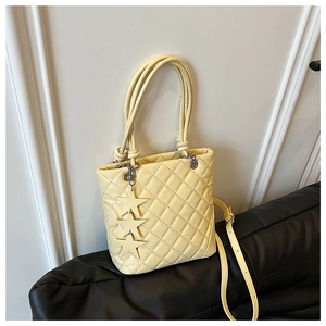 Détail du sac seau matelassé jaune clair avec pendentifs étoiles et surpiqûres en cœur
