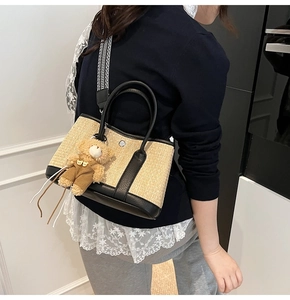 Détail d'un sac cabas en paille avec anses en cuir noir et bandoulière géométrique