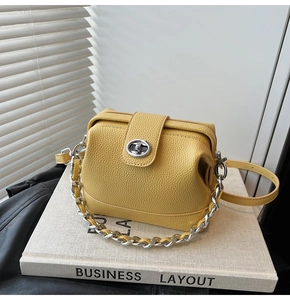 Detail of ginger yellow lychee leather handbag with silver chain and twist lock hardware