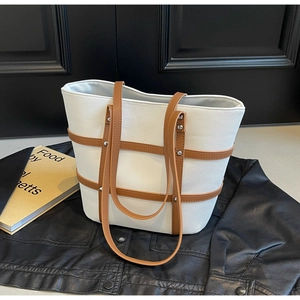 Detailed close-up of white canvas tote bag with brown leather straps and metal rivets