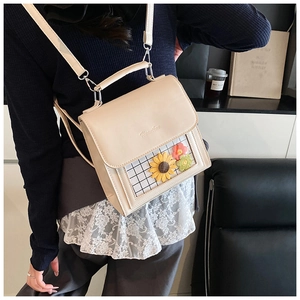 Detail of cream square backpack featuring sunflower patterns and transparent grid window