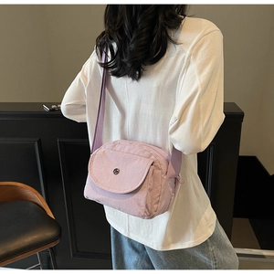 Detailansicht der lila Nylon-Umhängetasche mit Klapptasche und Gurt am Model getragen