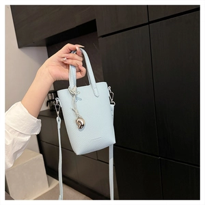 Détail macro du mini sac en cuir bleu clair à motif litchi avec pendentif cœur doré