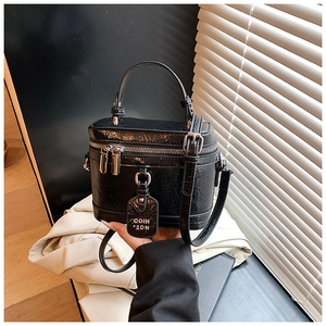 Detail of black glossy crinkle leather mini box bag with silver zippers and hand strap