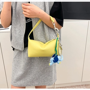 Dettaglio della borsa a tracolla in pelle gialla con charm a elefante blu e fibbie argento